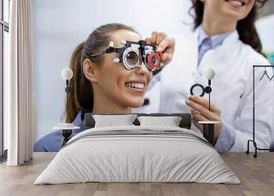 Ophthalmologist examining woman with optometrist trial frame. female patient to check vision in ophthalmological clinic Wall mural