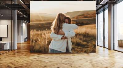 A mother embracing her daughter in a sunset in a majestic mountain landscape Wall mural