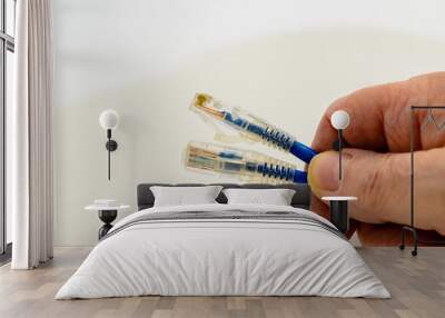 Close-up view of a man's hand holding two network cables against a white background. Wall mural