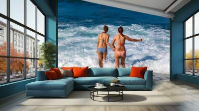 summer beach two girl friends with bikini hands by hands into the sea water crete greece Wall mural