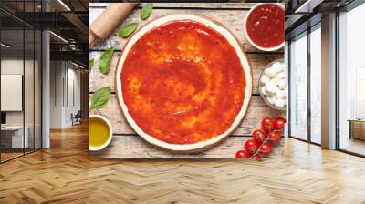 Raw dough for pizza preparation with ingredient: tomato sauce, mozzarella, tomatoes, basil, olive oil, cheese, spices served on rustic wooden table. Flat lay style. Italian pizza margheritafood Wall mural