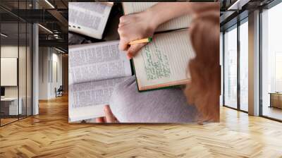 Girl holding a Bible. Сoncept for faith, spirituality and religion. Hand with pen taking notes from an open book Bible. Wall mural