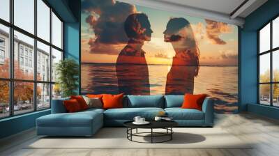 Double exposure of two silhouettes, one male and the other female, standing hand in hand on an ocean beach at sunset with clouds in the sky Wall mural