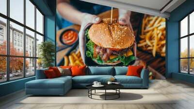 person holding up two different burgers with fries on the tray below, one of them is plant-based burger and other normal chicken sandwich Wall mural