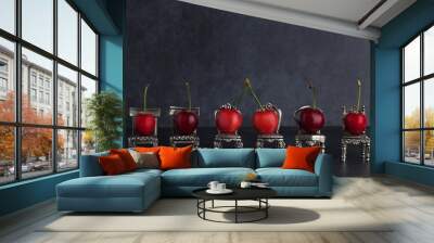 Row of red delicious cherries placed on tiny vintage silver chairs on dark background with copy space Wall mural