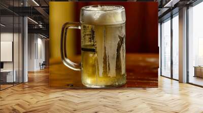 Refreshing Glass of Cold Beer Sitting on a Wooden Table in a Cozy Bar Setting Wall mural