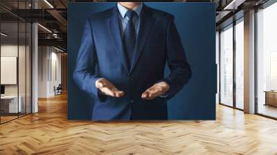 Man in suit holds hands with palms up. Wall mural