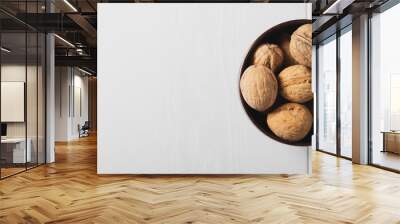 Walnuts on a white table in a small wooden plate, place for an inscription Wall mural