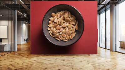 Yellow pumpkin seeds on a red background, top view Wall mural