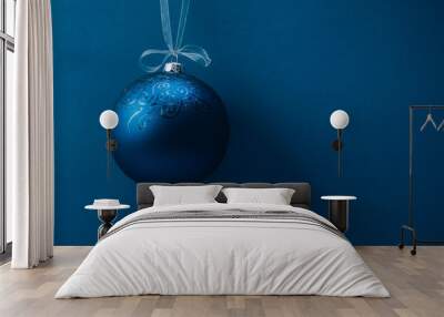 Christmas ball hanging on a ribbon over blue background. Copy space. Wall mural