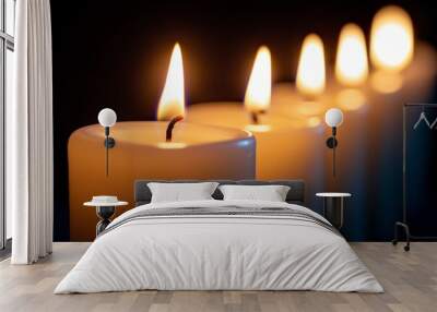 A row of white candles in a dark room, all but one unlit, creating a striking contrast.  Wall mural