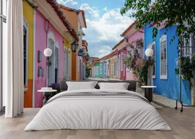 A street in a historic town, with the houses painted in a rainbow of pastel colors.  Wall mural