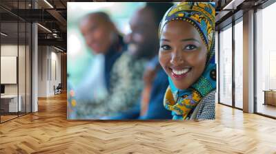 African American woman wearing a hijab smiling while sitting at a table with other people in a conference room Wall mural