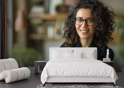 Portrait of a business woman with curly hair and glasses standing in an office. Wall mural