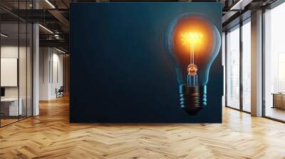 A glowing light bulb on a dark blue background. Wall mural