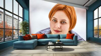 Red hair of young woman with serious look inside. Wall mural