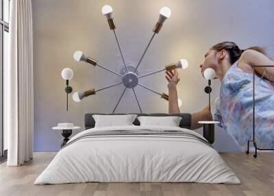 Replacing light bulb in LED lamp by woman indoors. Wall mural