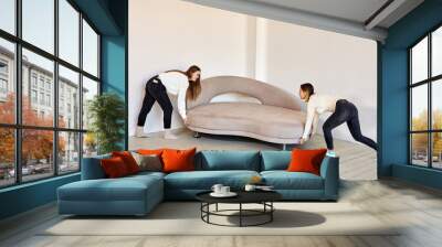 Two women move new sofa in lounge. Wall mural