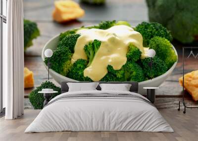 Broccoli with cheese sauce in white bowl on wooden table Wall mural