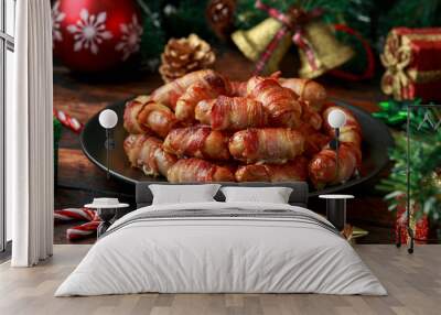 Christmas Pigs in blankets, sausages wrapped in bacon with decoration, gifts, green tree branch on wooden rustic table Wall mural