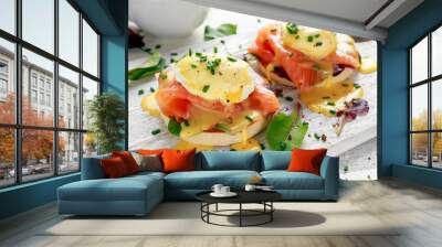 Eggs Benedict on english muffin with smoked salmon, lettuce salad mix and hollandaise sauce on white board Wall mural