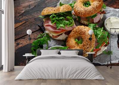 Fresh Bagels Sandwiches with cream cheese, bacon, tomato and green wild rocket on rustic wooden table Wall mural