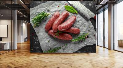 Freshly made raw breed butchers sausages in skins with herbs on crumpled paper. Wall mural