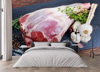 Raw lamb leg on blue stone background with herbs Wall mural