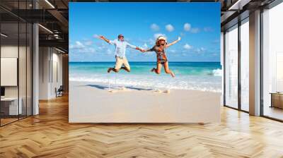 Happy couple jumping on the beach. Wall mural