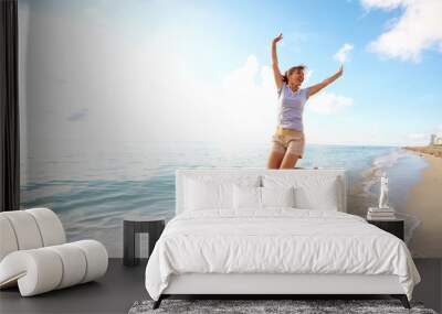 Happy woman jumping on the beach. Wall mural