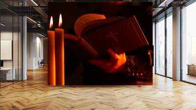 A person reads the Bible. Protestant with a Bible in his hands against the background of burning candles. Scripture reading. Communion with God. Faith in Jesus Christ. Christianity concept. Wall mural