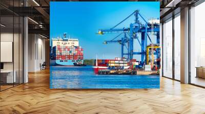 Cargo seaport. Freight ferry leaves for the sea. Concept - unloading of cargo ships. Concept - cargo delivery by sea. The ship departs from the port. Sea port on the background of blue sky Wall mural