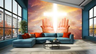 Christian crucifix. Hands praying Catholic. Christian cross in sky. Christian hands before sunset. Religious crucifix on background sky. Catholic crucifix in clouds. Concept turning to god for help Wall mural