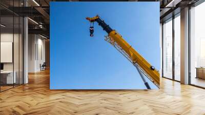 Crane boom. Construction equipment. Tower crane boom with cargo hook. Fragment of construction crane against sky. Equipment for unloading at port. Hydraulic lifting equipment on blue Wall mural