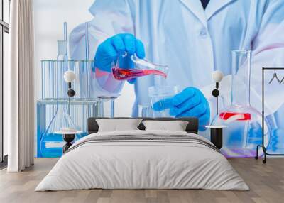 Laboratory assistant conducts experiments with chemical liquids. The man mixes the substances. Checking the interaction of reagents. Testing of food samples. Analysis of the company's products. Wall mural