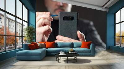 Man holds a smartphone in front of him. Concept businessman makes a video call. Video communication for business activities. Video call to a business partner. Blurred businessman in the background Wall mural