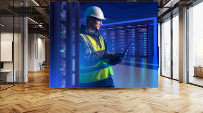 Man in server room. Hosting provider engineer. Programmer with laptop. Guy is setting up server hardware. Man in reflective vest and helmet. Telecommunication technologies. Provider company employee Wall mural