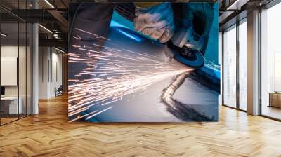 Man polishes metal. Master works with a grinding machine. Leveling material. Concept - alignment of car body. Body work in a car workshop. Sparks fly from under grinding machine. Angle grinder Wall mural