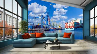 Ship in seaport. Sea vessel with containers on board. Cargo harbor with cranes for loading. Seaport on sunny day. Ship with containers on background blue sky. Port for loading ships. Modern seaport Wall mural