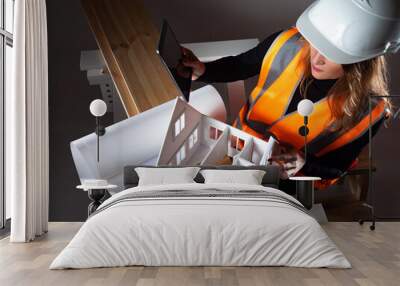 Top view carpenter woman portrait. Carpenter woman in hard hat and orange vest. She holds the tablet in her hands. Carpenter woman next to wood planks. Concept - she makes home furniture. Wall mural