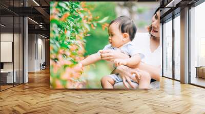 mother with little child in white blooming garden. woman with son in green leaves,happy family outdoors in spring Wall mural