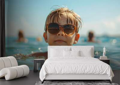 Funny young boy in sunglasses swimming in the sea, full of summer fun and splashes Wall mural