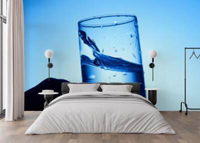 closeup of pouring water on the cup on transparent blue background Wall mural