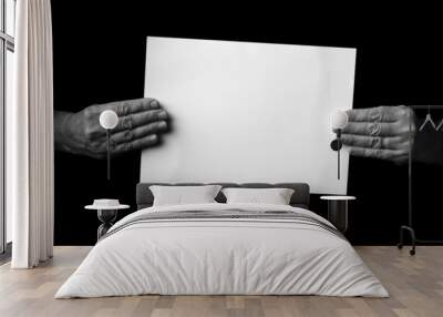 Hands holding blank sheet of paper against black background. Wall mural