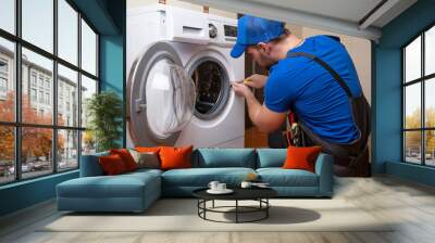 Working man plumber repairs a washing machine in home. Washing machine installation or repair. plumber connecting appliance Wall mural