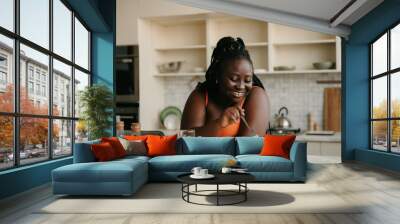 Beautiful curvy African woman enjoying healthy eating for lunch at home Wall mural