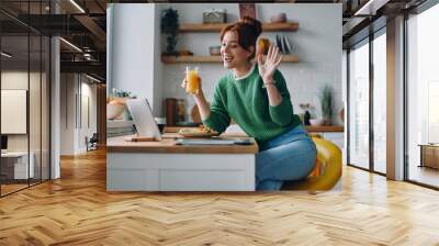 Beautiful young woman having video call while dinning at the domestic kitchen Wall mural