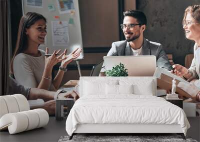 Happy business team working together while sitting at the desk in office Wall mural