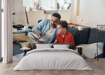 Happy father helping his son with homework while homeschooling in the living room Wall mural