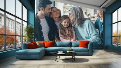 Happy multi-generation family bonding while sitting on the sofa at home together Wall mural